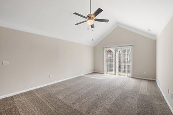 an empty living room with a ceiling fan and a window at Cidermill Village Apartments in Rochester Hills, MI 